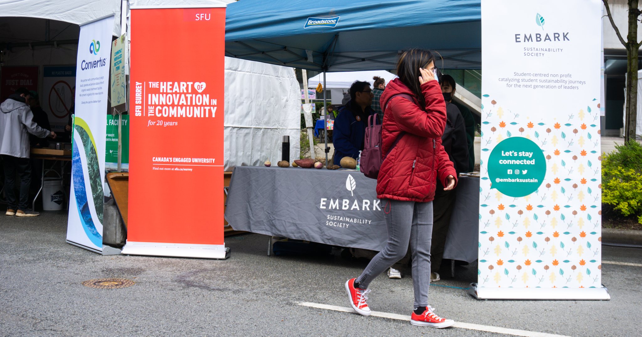 Person walks in front of an Embark outreach table.