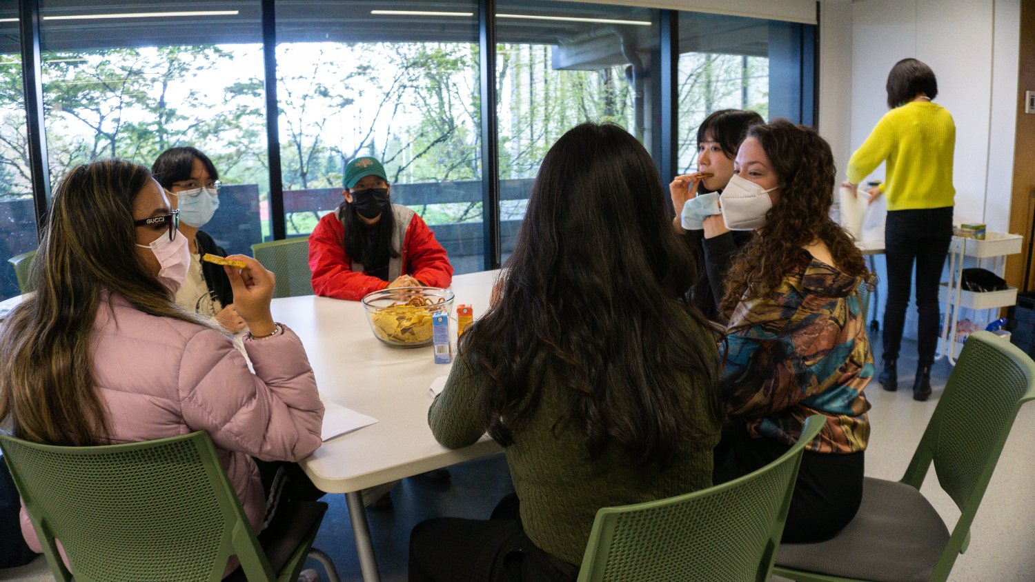 Student gather in discussion around a table.